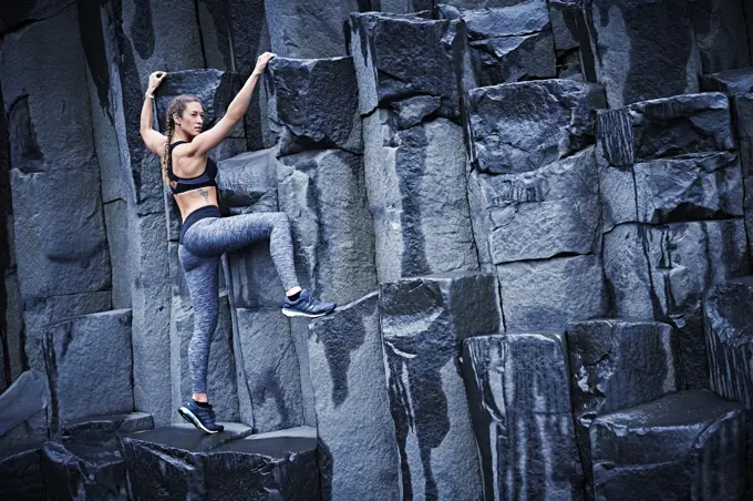 Happy confident young women climbing on basalt rock in southern Iceland.