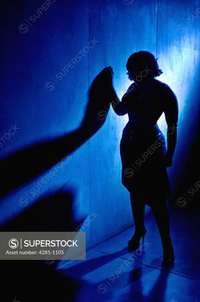Silhouette of a woman leaning against the wall, with blue light.
