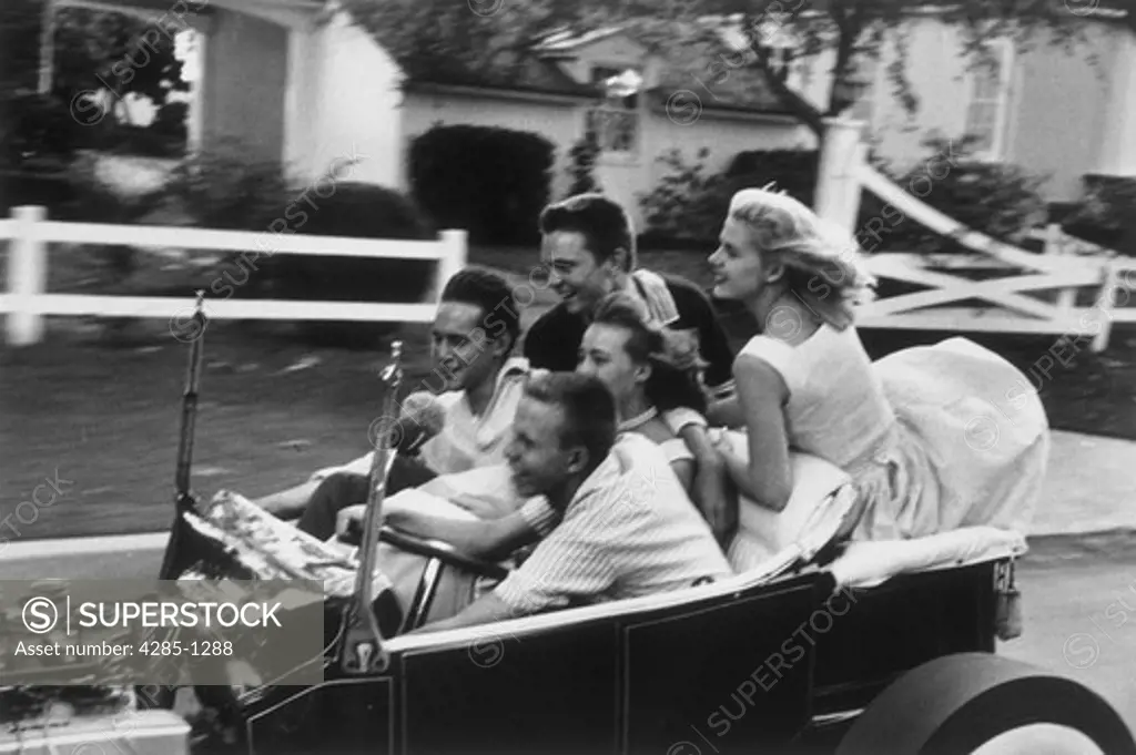Group of teenage boys and girls take a joyride in a vintage 1950s convertible.   Image was taken in the 1950s.