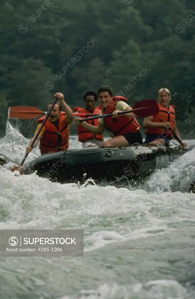 Four young men white water rafting through rapids.