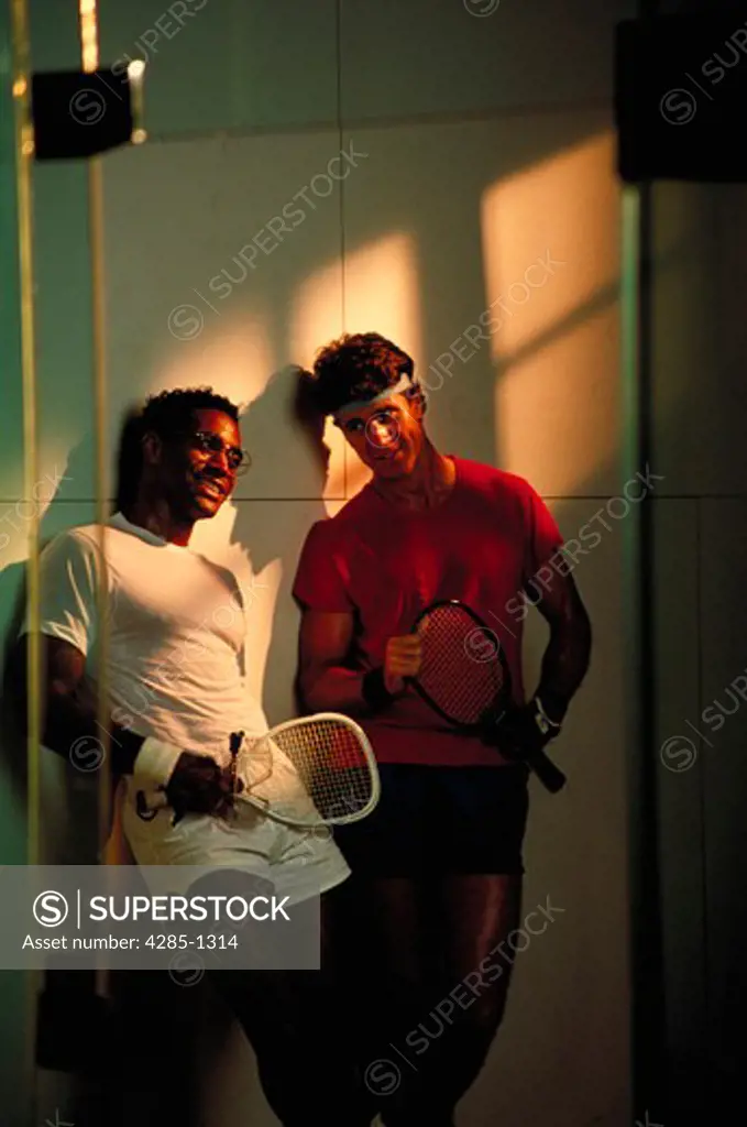 Two men talking in the locker room after playing racquetball.