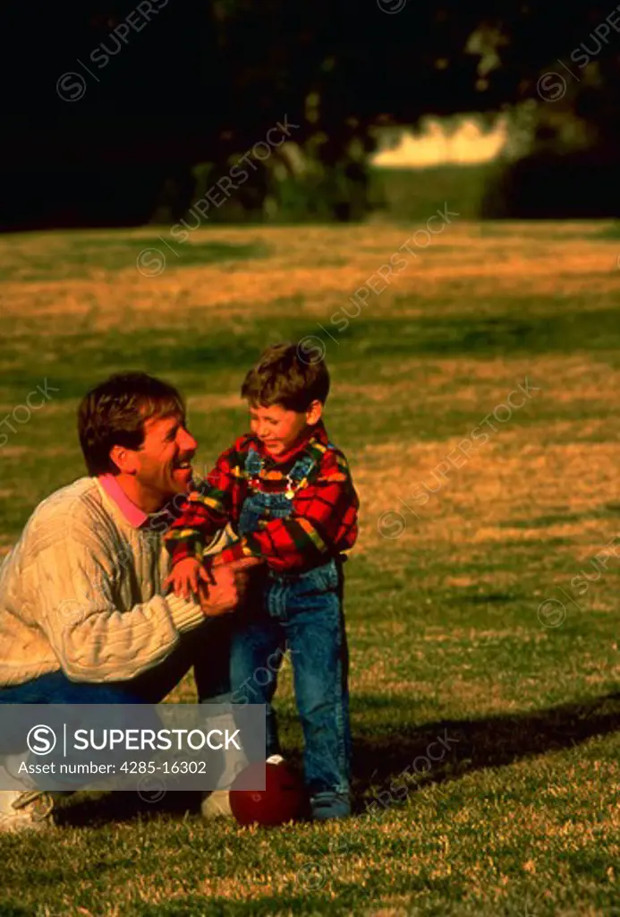 Having Fun Together  Father and son playing football in the park. MR