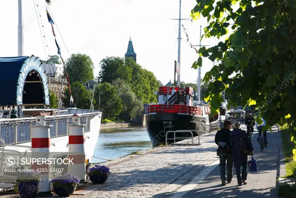Finland, Region of Finland Proper, Western Finland, Turku, Aura River, Riverbank, Moored Ships, Pedestrians, Turku Cathedral Tower
