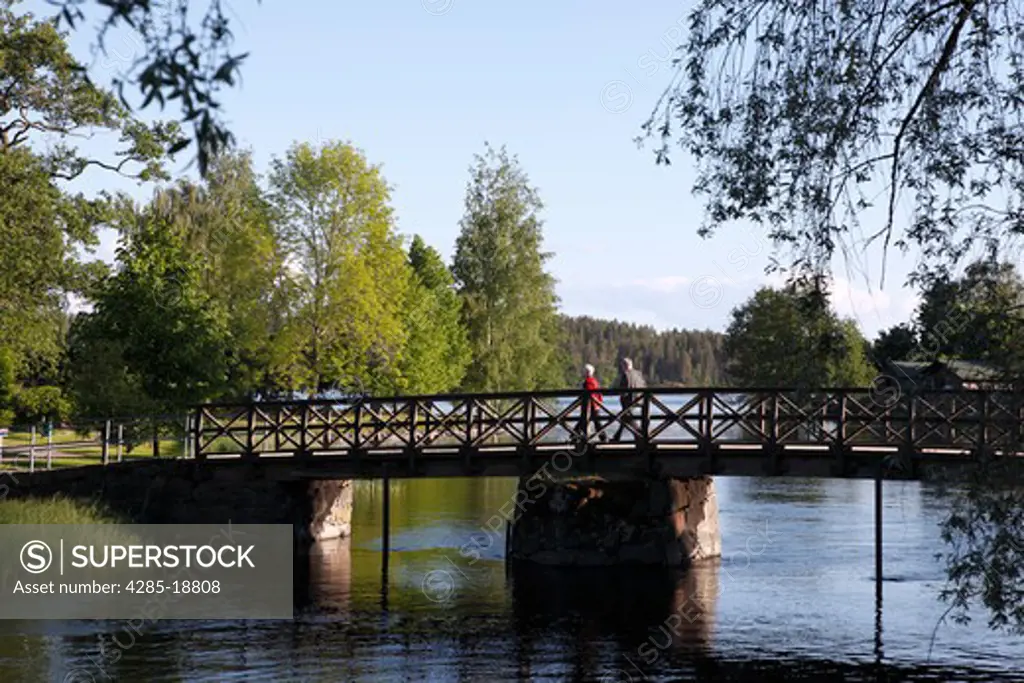 Finland, Region of Southern Savonia, Saimaa Lake District, Savonlinna, Couple Walking on Bridge to Olavinlinna Castle, St. Olaf's Castle