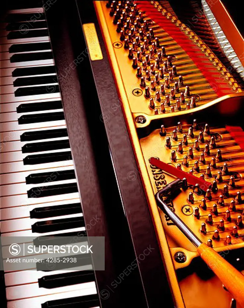 Close-up of a piano key board, the interior mechanics of a piano and a tuning tool.