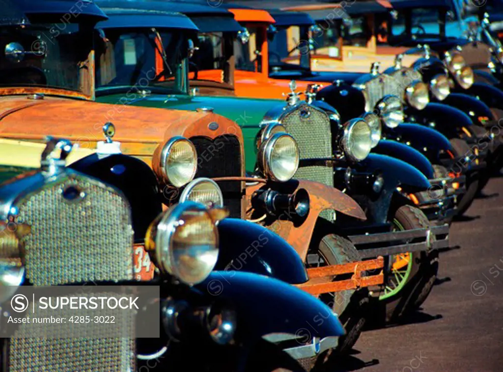 An assortment of antique cars in a row.