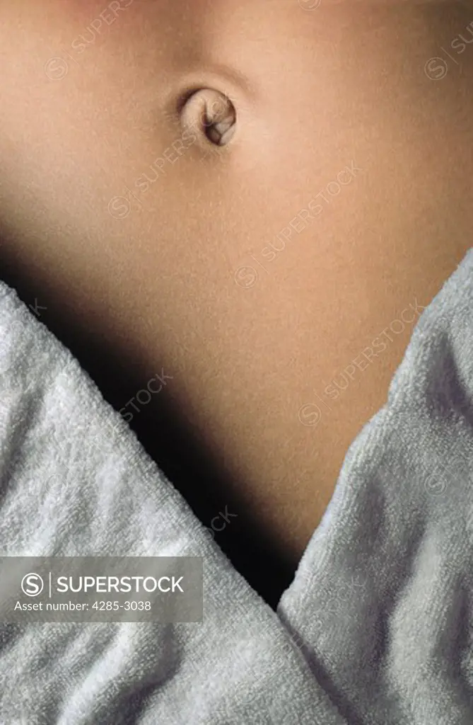 Girl torso and belly button, tanned, with white towel, close-up.