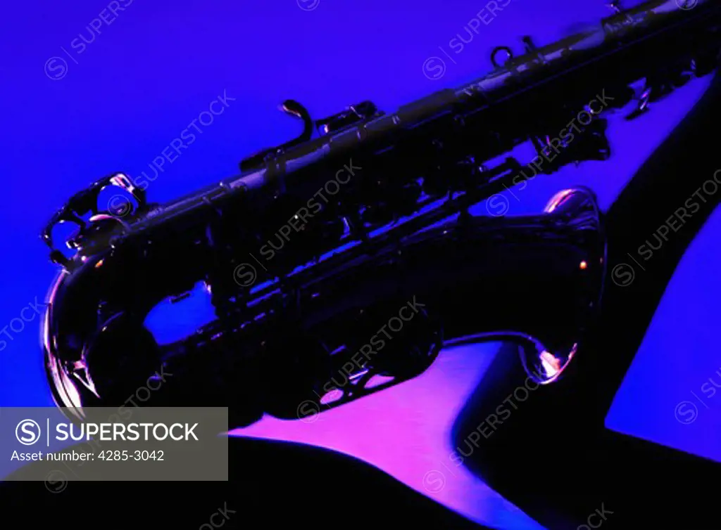 Girl torso in silhouette, arm holding Saxophone on hip with deep blue and magenta background.