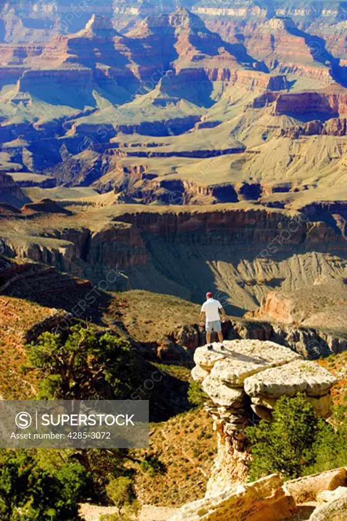 Man standing on edge of rock precipice overlooking Grand Canyon.