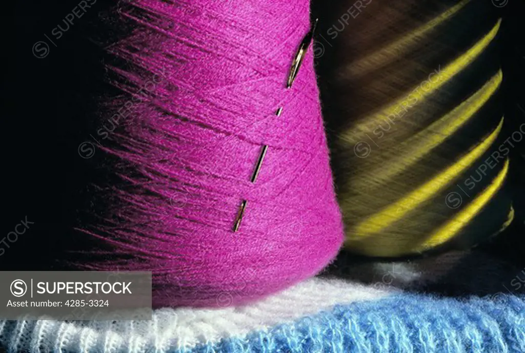 Cotton string rolls, magenta and yellow with thick metal needle.  Blue and white cotton surface