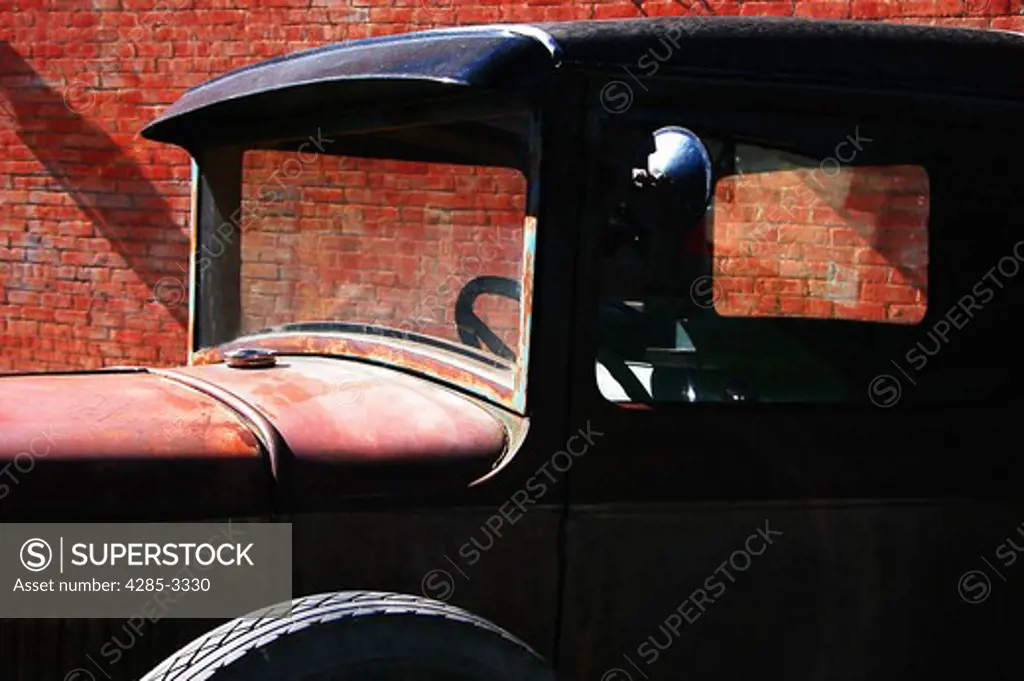 Rusted old vintage car.  Ford.  With brick background.