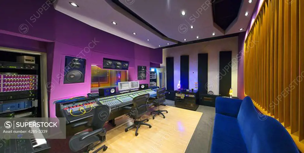 Music recording studio wide angle panoramic shot with array of control panels and sitting area.