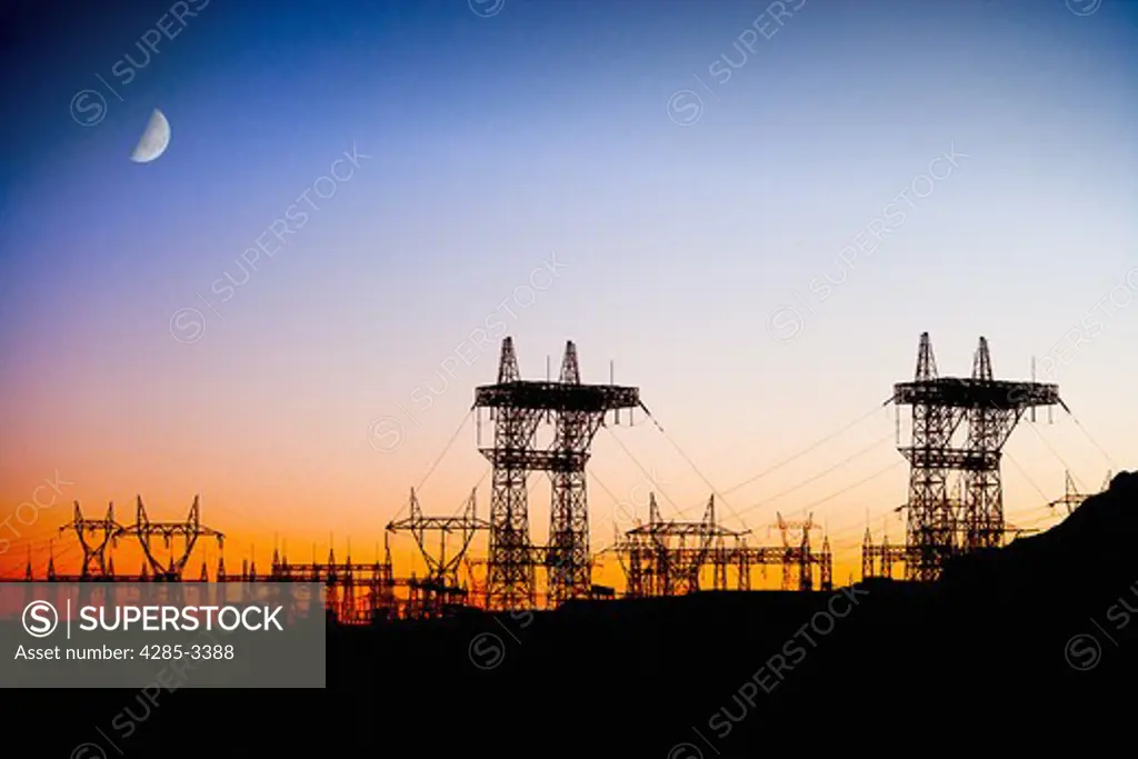 Power lines in silhouette with sunset and dark blue sky and moon, Navajo Indian reservation power plant at Lake Powell, Arizona / Utah.