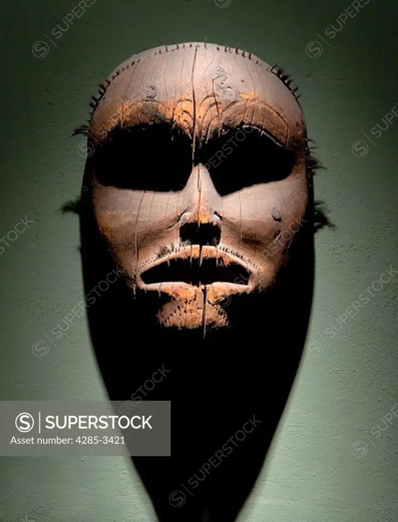 Native American wood mask with dramatic lighting hanging from wall