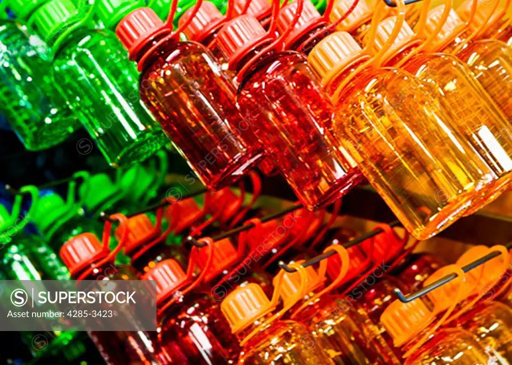 colorful plastic bottles, red, orange and green stacked and hanging in a row, showing patterns.