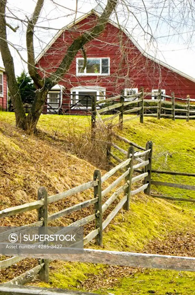 Farm scene with red barn in background and wood fence leading into the shot.