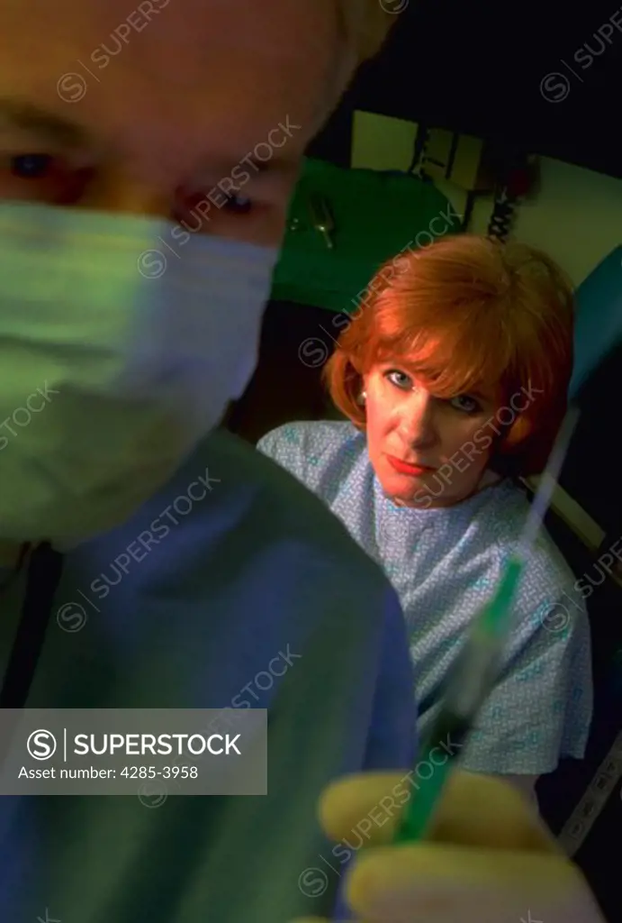 Female patient looking scared as doctor prepares hypodermic needle.