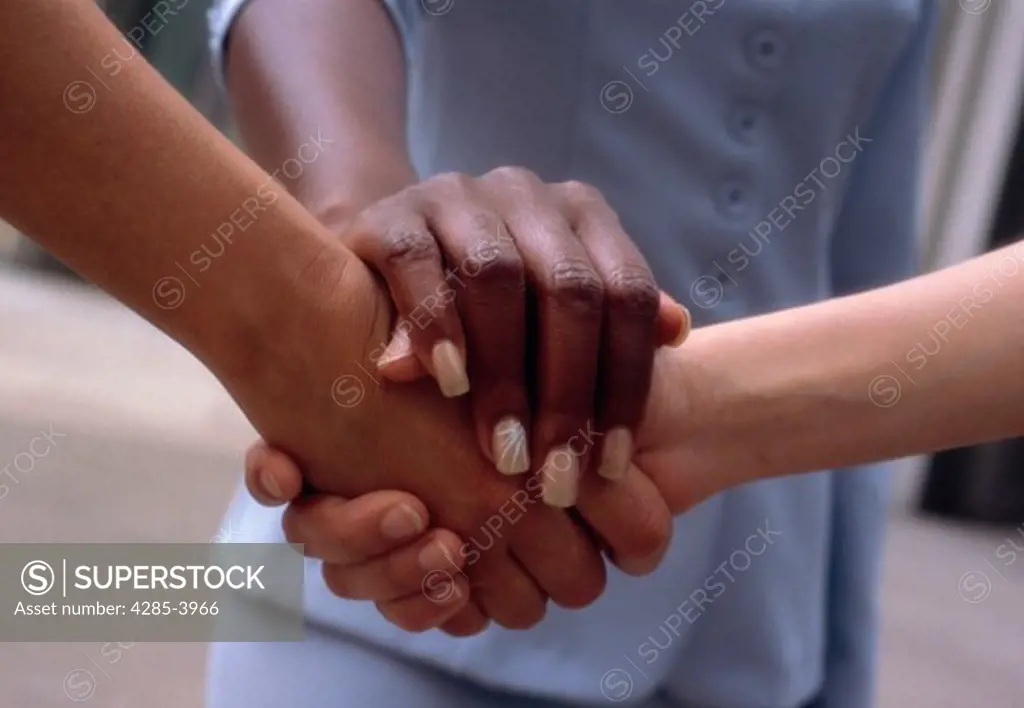 An African American person, a Caucasian person and an Asian person all join hands to show multi-ethnic unity.
