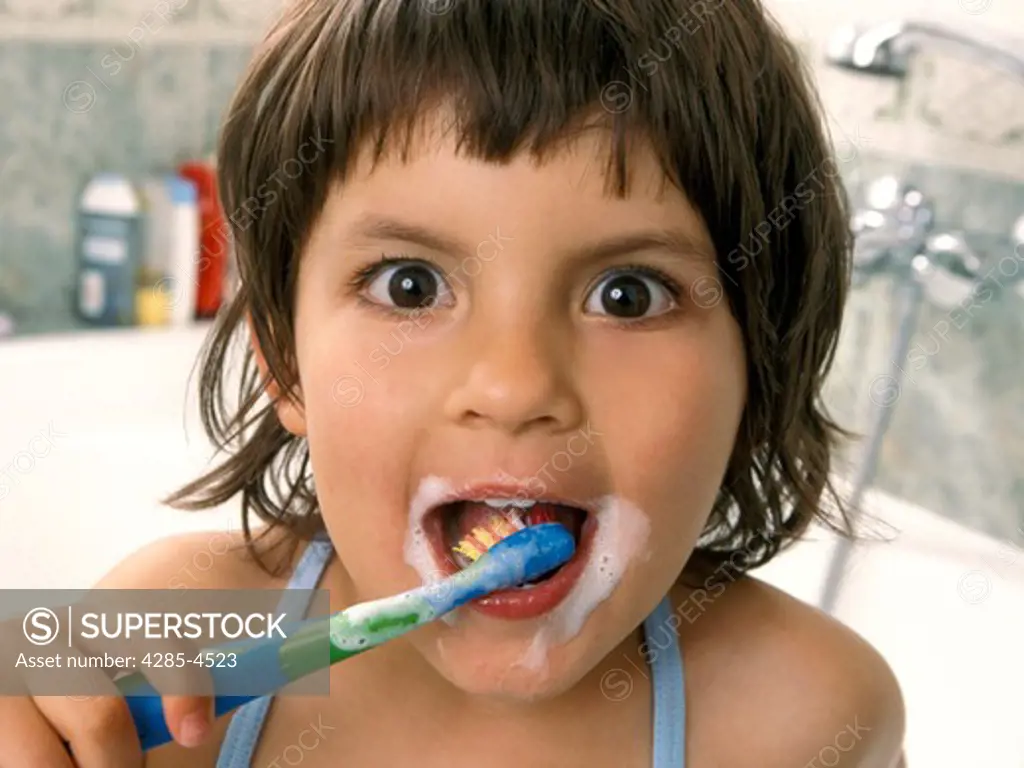 Girl brushing teeth in bathroom, big eyes