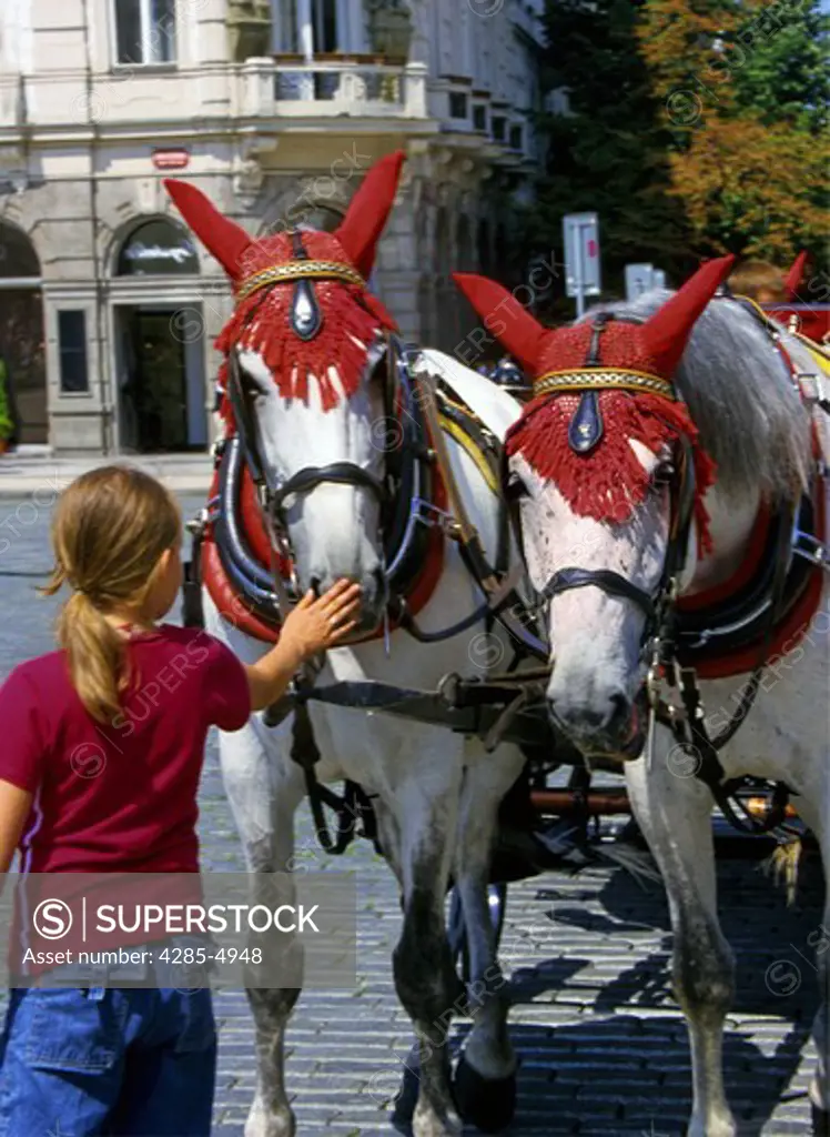 Girl touching horse Carriages at Old Town Square in Prague Czech Republic