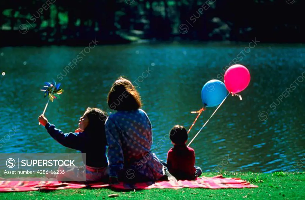 Mother and children sitting by lake, MR