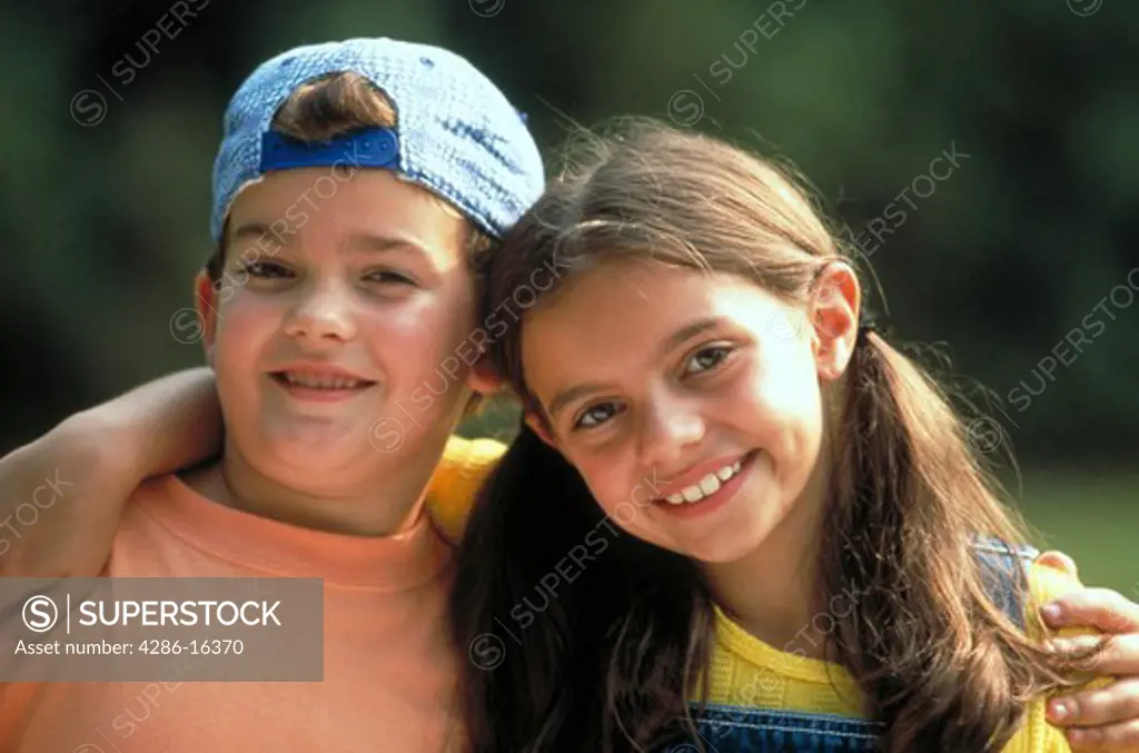 Boy and girl with arms around eachother smiling.