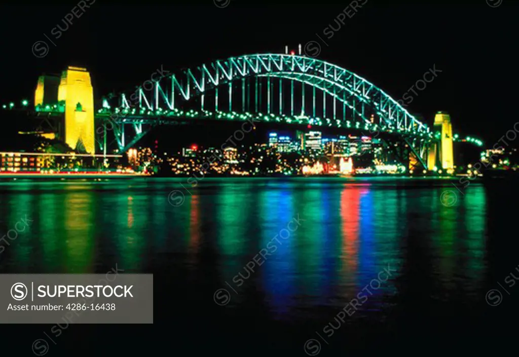 Lights from the city and the Sydney Harbour Bridge reflected in Sydney Harbour, Sydney, Australia at night.