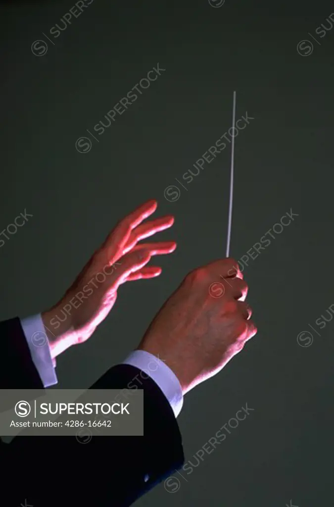 Close-up of a conductors hands with a baton in one hand.