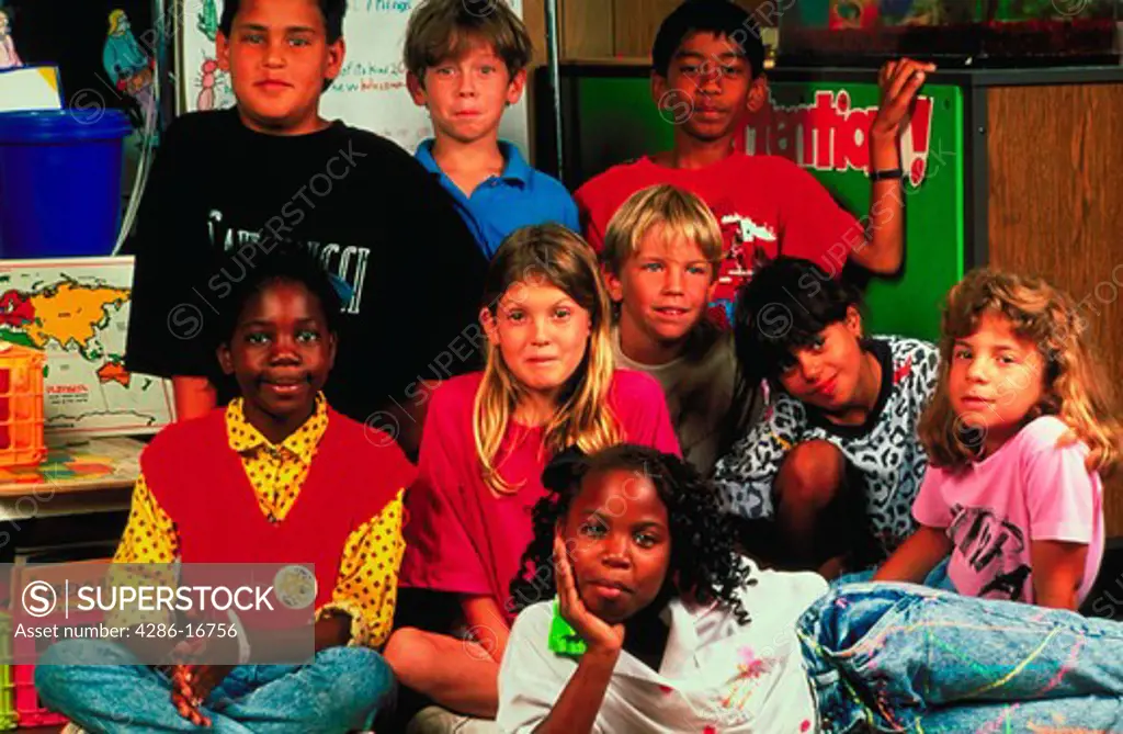 Portrait of nine ethnically diverse elementary school children inside a classroom.