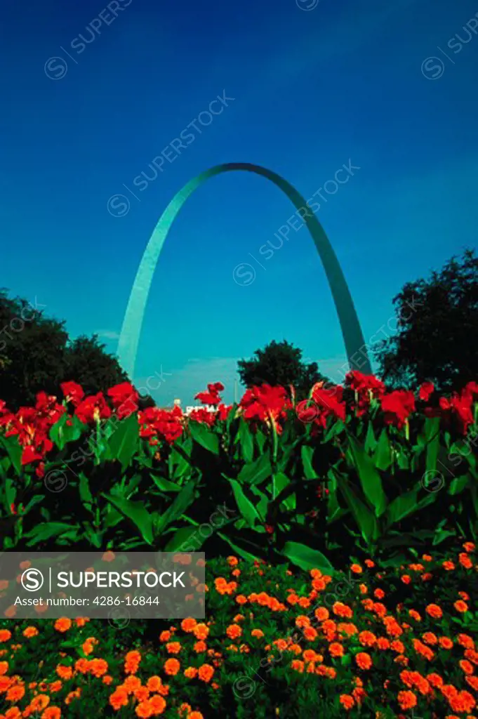 View looking across a patch of colorful flowers up at the Gateway Arch against a bright blue sky in Saint Louis, Missouri.
