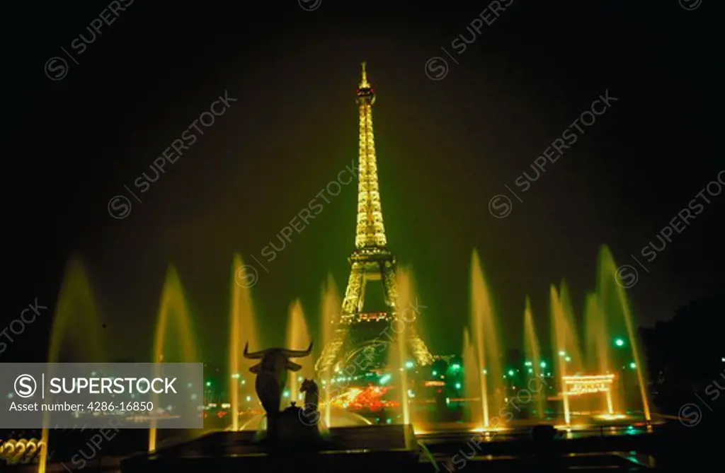View of the Eiffel Tower in Paris, France illuminated at night with fountains in the foreground.