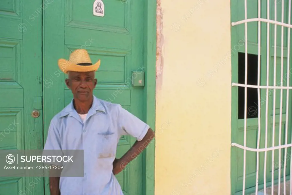 Man standing in front of a green door in a colonial village of Trinidad, Cuba. 