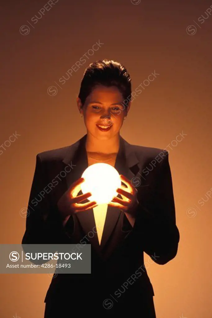 Woman gazes into glowing ball.