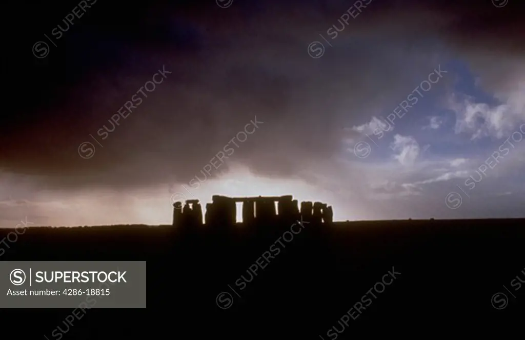 Silhouette of rock formation of Stonehenge against dark sky and storm clouds.