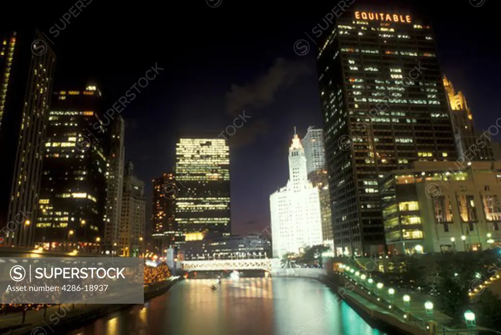 Chicago, Illinois, The illuminated skyline of downtown reflects in the waters of the Chicago River at night. The white Wrigley Building is illuminated in the background.