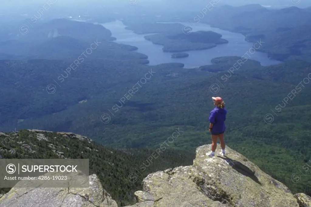 Adirondacks, Adirondack Park, New York, Woman standing on summit of Whiteface Mountain in Wilmington in the state of New York looking at Lake Placid and scenic view. 
