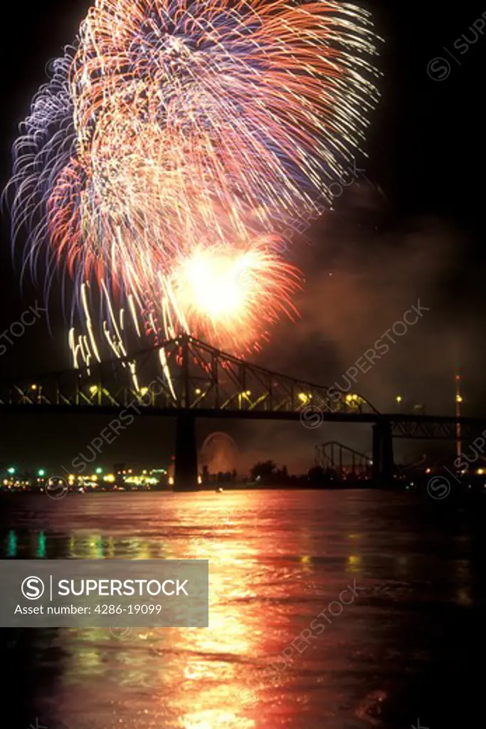 Canada, Quebec, Montreal, Firework display from the Benson & Hedges International Firework Competition reflects on the St. Lawrence River (Fleuve Saint-Laurent) at night in Montreal. Pont Jacques Cartier 