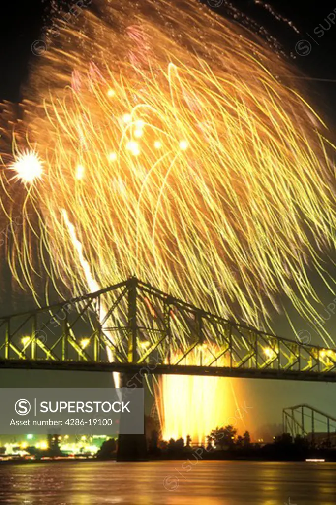 Canada, Quebec, Montreal, Firework display from the Benson & Hedges International Firework Competition reflects on the St. Lawrence River (Fleuve Saint-Laurent) at night in Montreal. Pont Jacques Cartier.