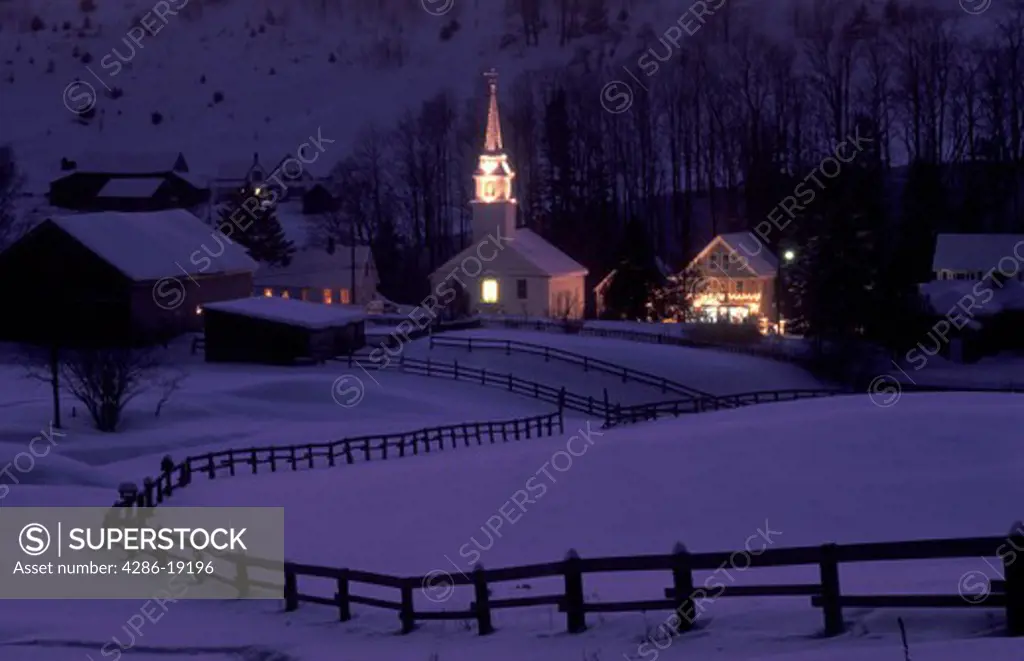 Vermont, church, A split rail fence stretches down a snow covered field towards the scenic village of East Corinth at night, evening.