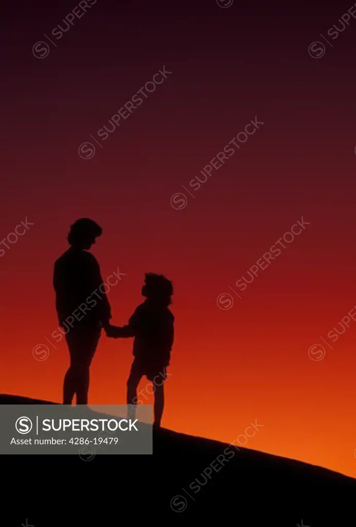 Silhouette, people, Stone Mountain, Georgia's Stone Mountain Park, Atlanta, Georgia, Silhouette of mother and young daughter holding hands and looking/watching at sunset on the summit of Stone Mountain in Georgia's Stone Mt. Park near Atlanta in the state of Georgia. 