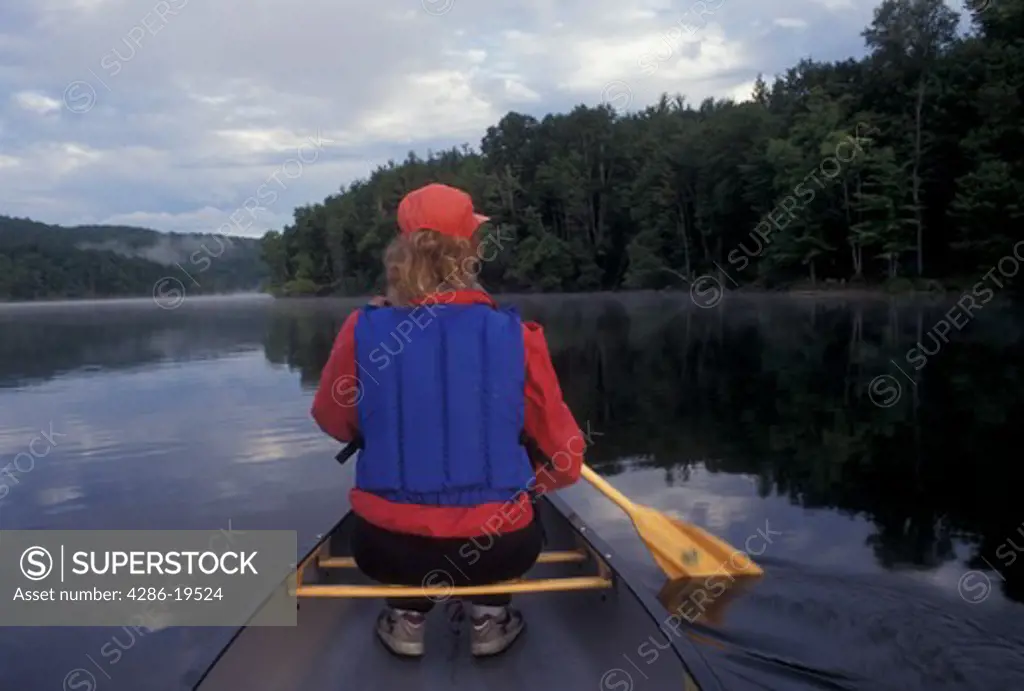 canoeing, canoe, Vermont, VT, Woman paddling a red canoe on Green River Reservoir in Hyde Park. 