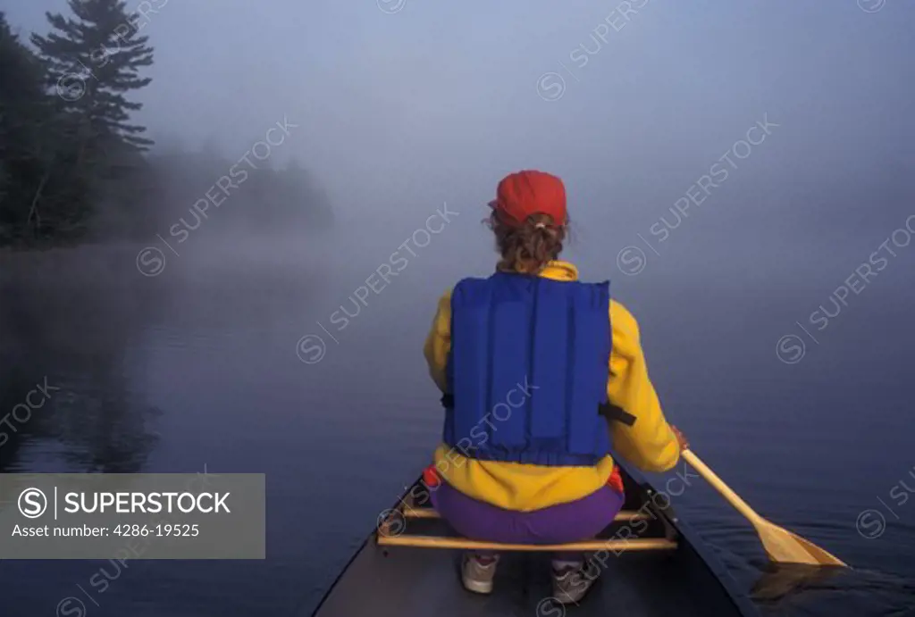 canoeing, canoe, Vermont, VT, Woman paddling a canoe on Kettle Pond in the fog in Groton State Forest.