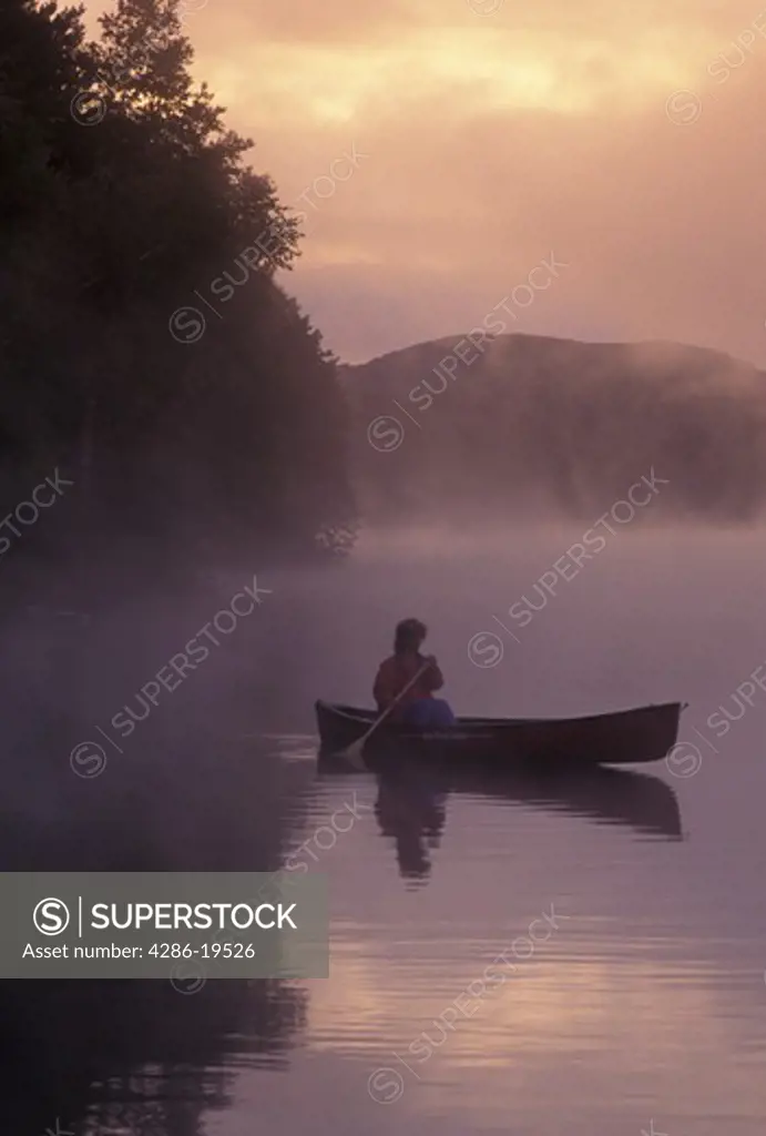 canoeing, canoe, sunrise, sunset, Vermont, VT, Woman paddling a canoe on Mollys Falls Pond at sunrise in the fog.