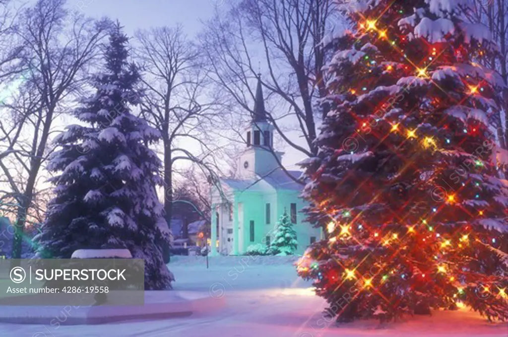 church, winter scene, chapel, christmas tree, decorations, village, town, winter scene, holiday, snow, Vermont, Picturesque view of The First Baptist Church of Bristol and a large evergreen tree on the Green decorated with sparkling colorful lights for the Christmas holiday season on a snow covered evening in Addison County in the state of Vermont. 
