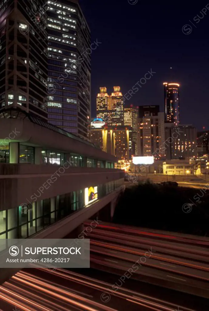 Atlanta, skyline, GA, Georgia, Skyline of downtown Atlanta. Streaks of car lights on Downtown Connector I-75/85 pass under the MARTA station in the evening.