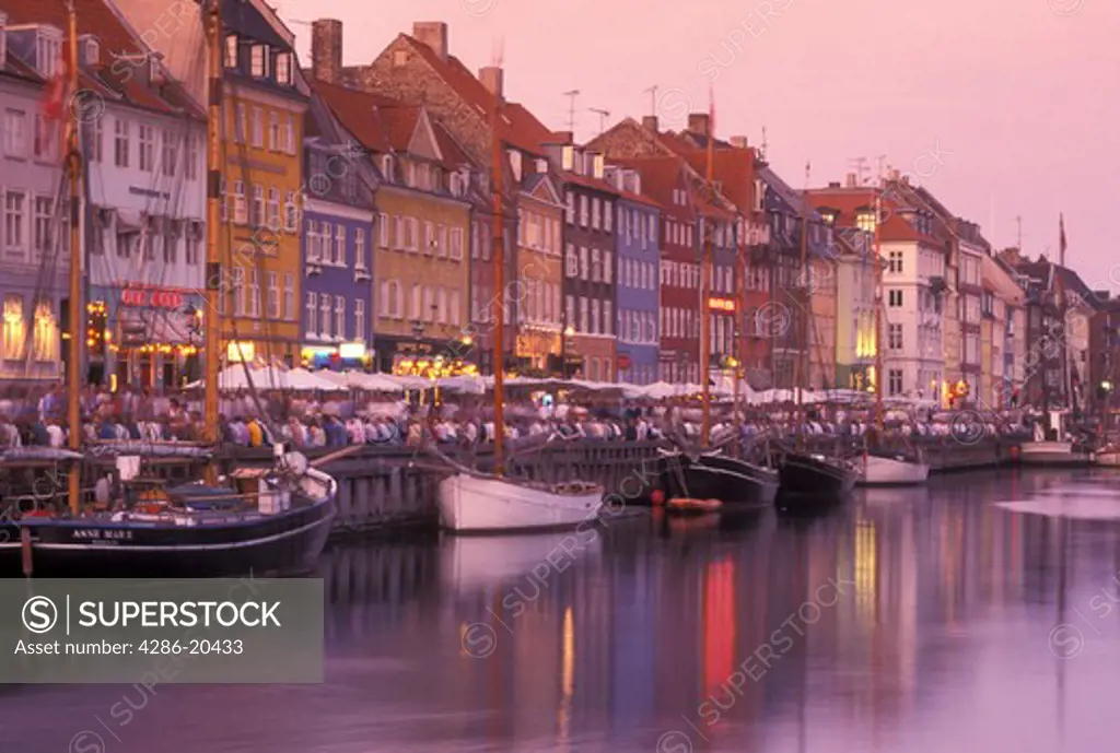 Copenhagen, Denmark, canal, Scandinavia, Sjaelland, Europe, Crowd of people along Nyhavn (New Harbor) in the scenic city of Copenhagen in the evening. Boats docked along the canal.