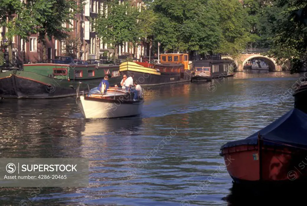 Amsterdam, Netherlands, Holland, Noord-Holland, Europe, Boat cruises down a canal in Amsterdam.