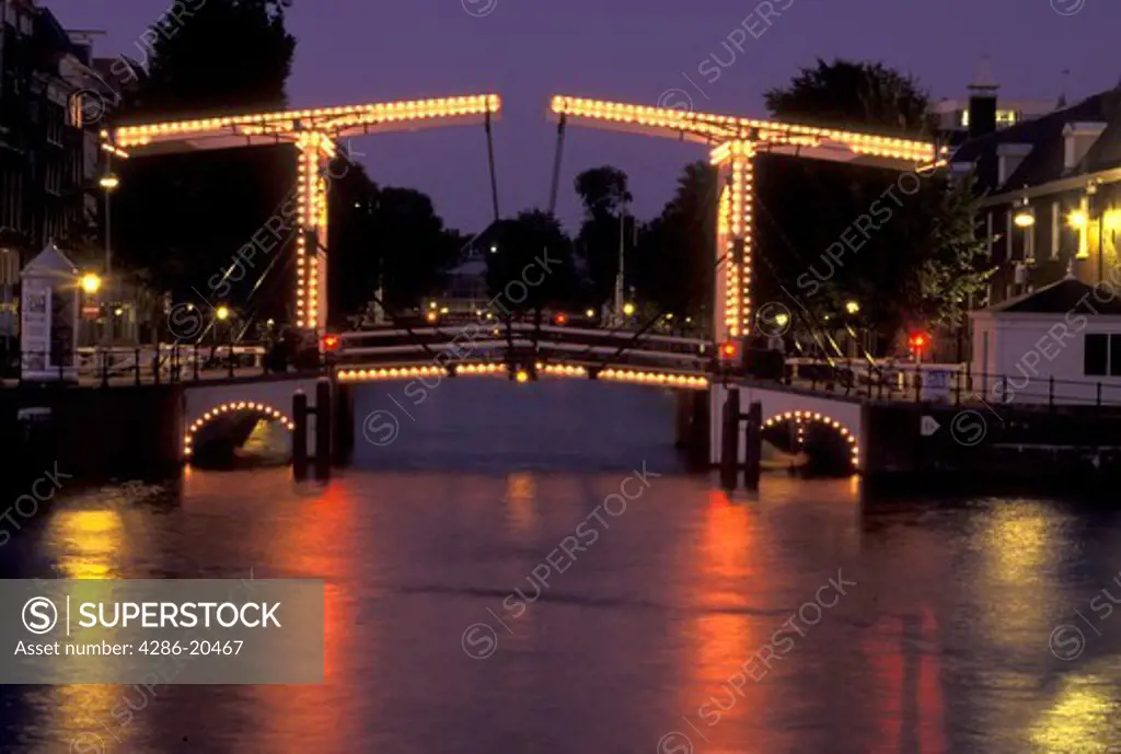 drawbridge, Amsterdam, Holland, Netherlands, Noord-Holland, Europe, Drawbridge illuminated at night on a canal in Amsterdam.