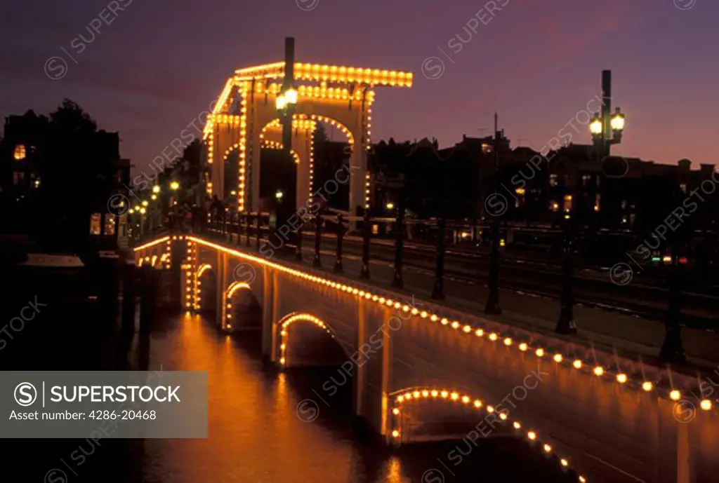 drawbridge, Amsterdam, Holland, Netherlands, Noord-Holland, Europe, Skinny Drawbridge illuminated at night on a canal in Amsterdam.
