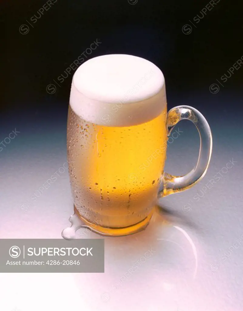Glass mug filled with golden beer with nice foamy head.
